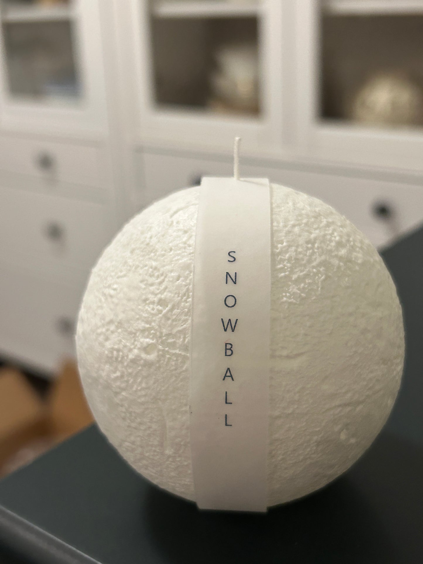 Snowball Candle surrounded by festive decorations, ideal for holiday celebrations.