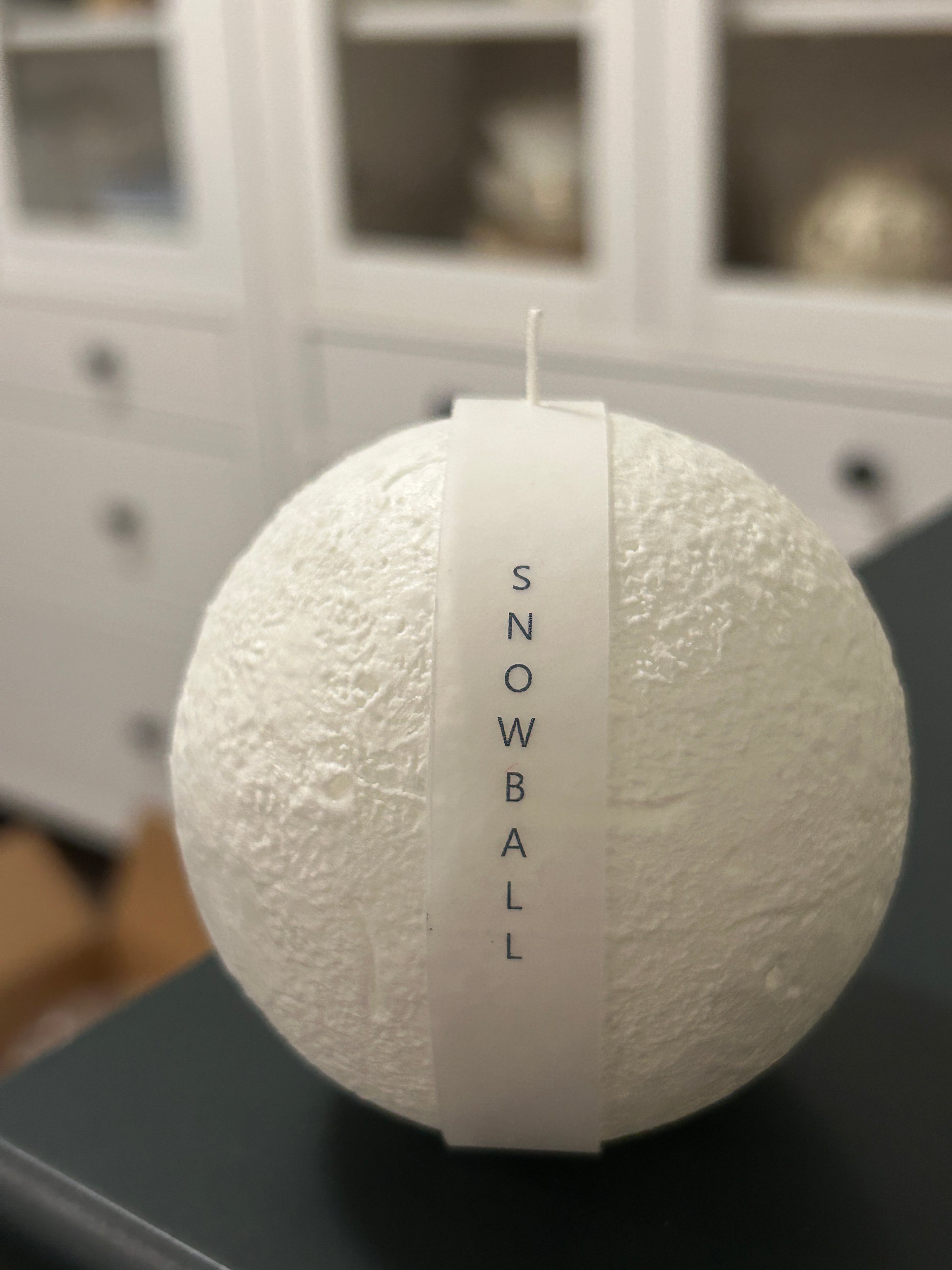 Snowball Candle surrounded by festive decorations, ideal for holiday celebrations.